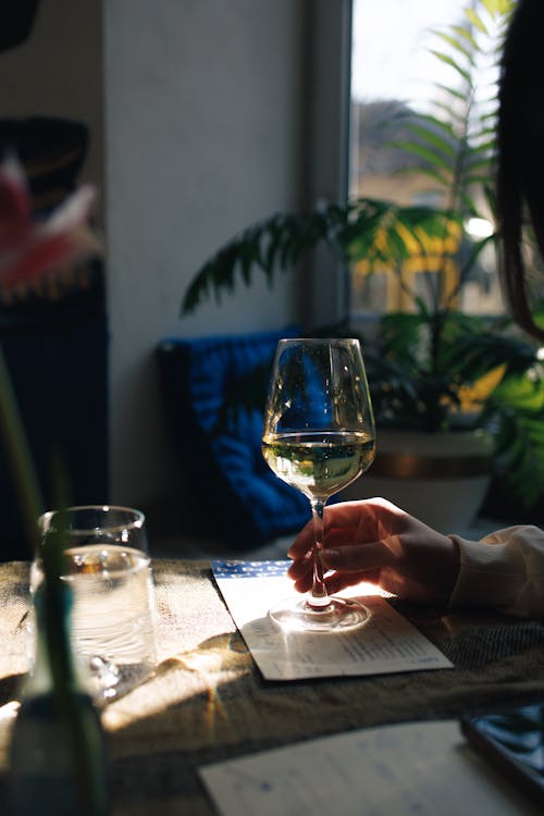 A person holding a glass of wine at a table