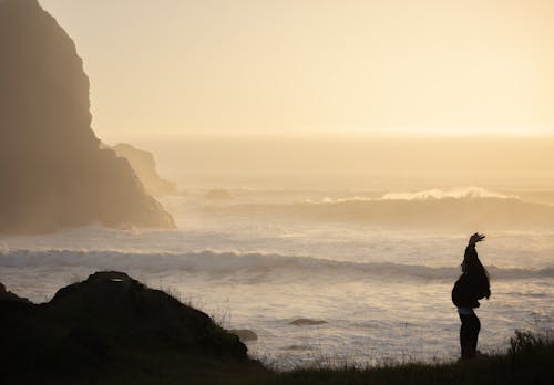 A person standing on a cliff overlooking the ocean