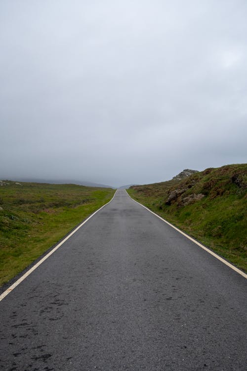A long empty road with a cloudy sky