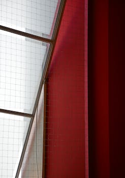 Abstract composition of red and white walls with geometric window design.