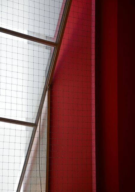 Abstract composition of red and white walls with geometric window design.