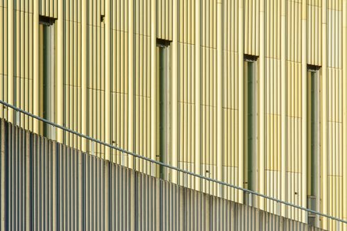 Free Close-up of a modern yellow facade with vertical patterns and windows. Architectural detail photography. Stock Photo