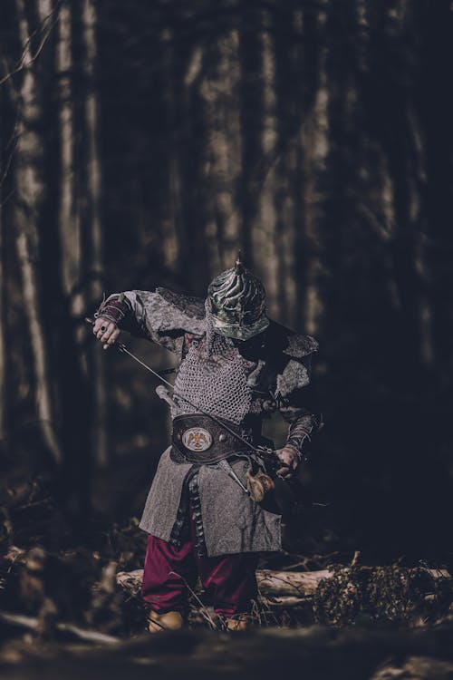 A man dressed in armor is standing in the woods