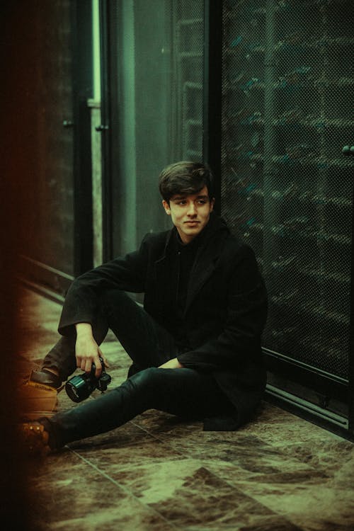 A young man sitting on the ground with his camera