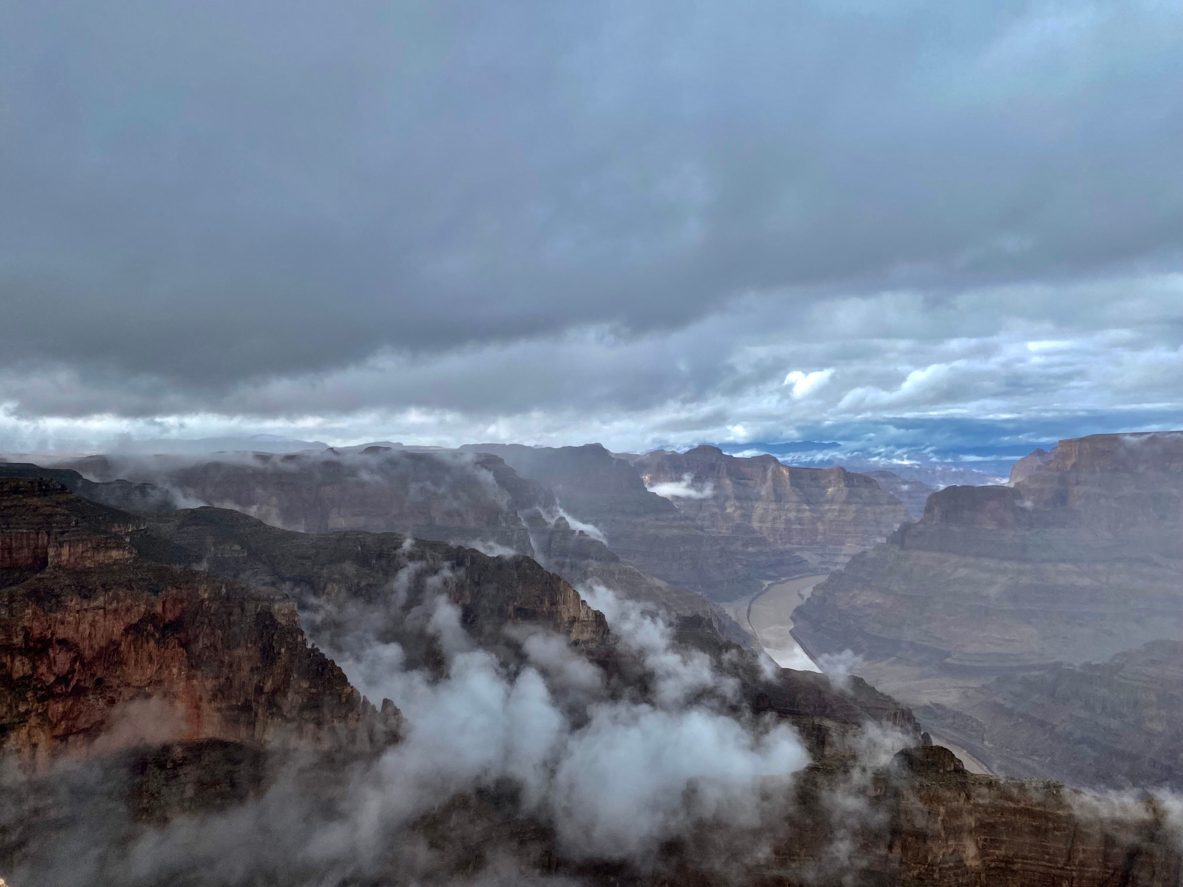 Extended Grand Canyon West Rim Air-Only Helicopter Tour - Breathtaking aerial view of a canyon landscape shrouded in clouds, showcasing natural beauty and dramatic skies.