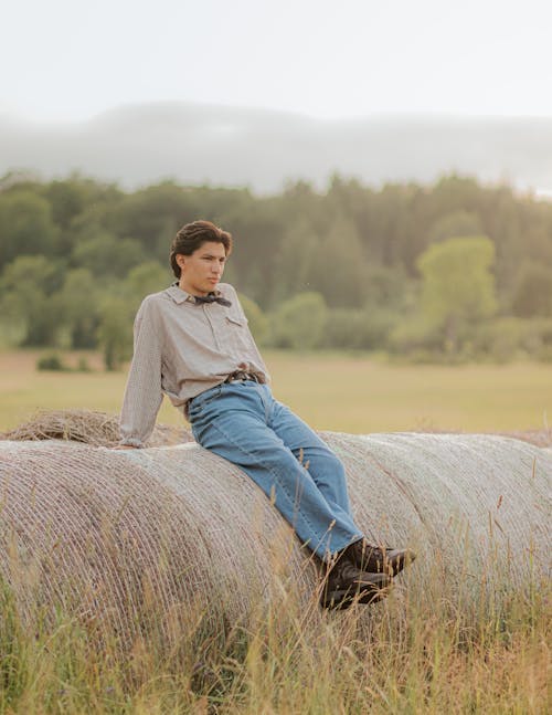 A man sitting on a hay bale in a field