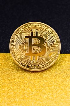 Vertical shot of a gold Bitcoin placed on a shimmering textured surface, symbolizing digital finance.
