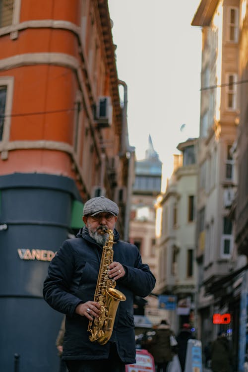 A man playing a saxophone in a narrow street