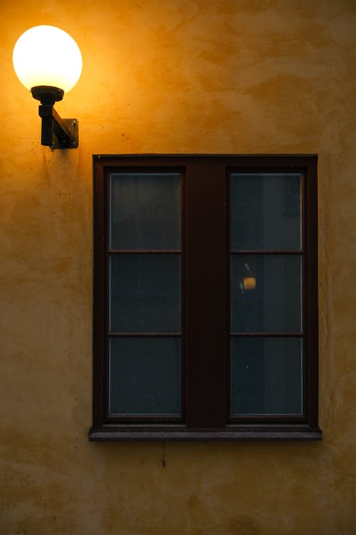 A window with a light and a lamp on the wall