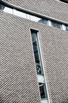 Modern facade featuring geometric design with narrow vertical window, showcasing minimalism and urban architecture.