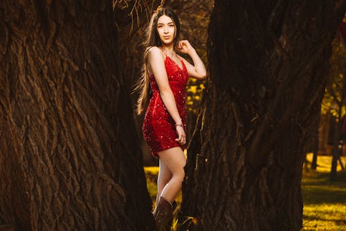 A beautiful young woman in a red dress posing in the woods