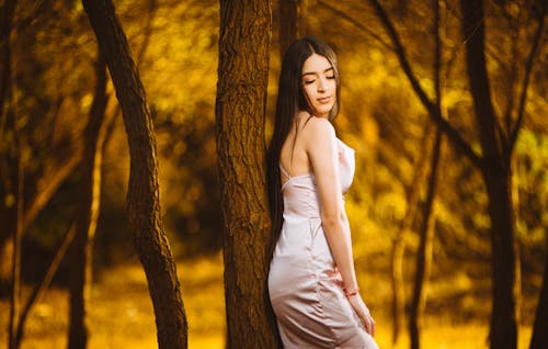 A woman in a white dress is standing in the woods