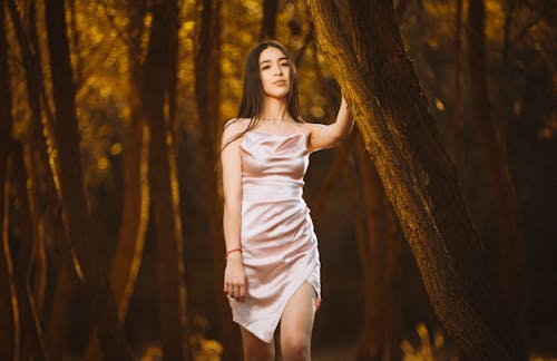 A woman in a pink dress standing in the woods
