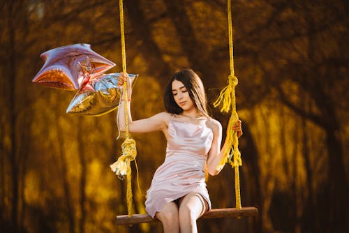 A woman sitting on a swing with balloons