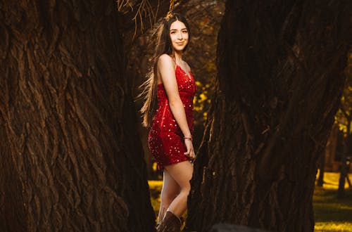 A girl in a red dress posing in the woods
