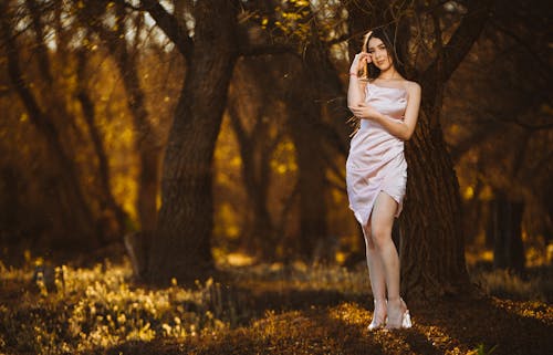 A woman in a white dress is standing in the woods