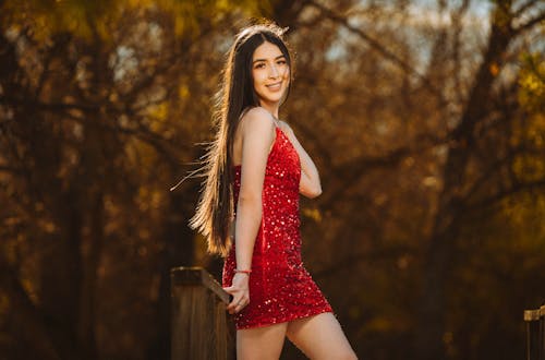 A beautiful young woman in a red dress posing for a senior portrait