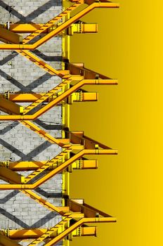Abstract view of a yellow industrial staircase against a brick wall background.