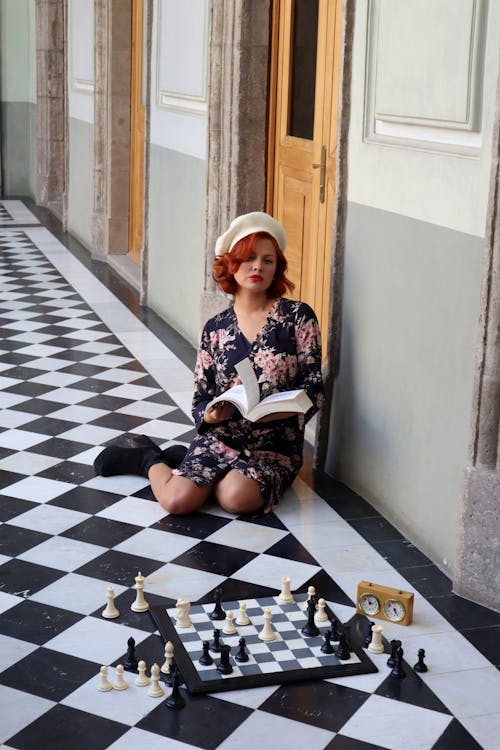 A woman sitting on the floor playing chess