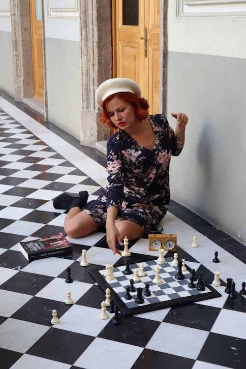 A woman sitting on the floor playing chess