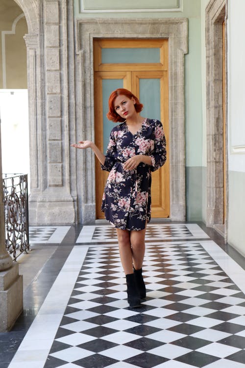 A woman in a floral dress standing on a tiled floor