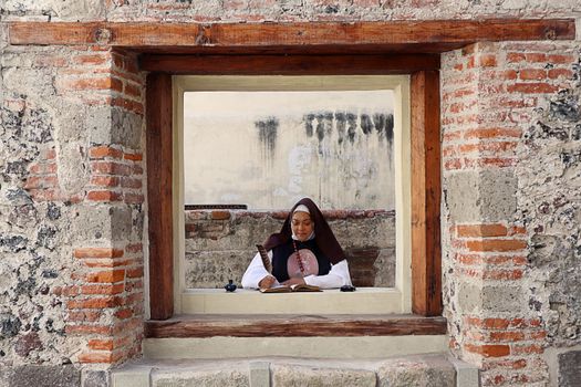 Nun Writing with a Feather and Ink in a Book while Sitting in a Window