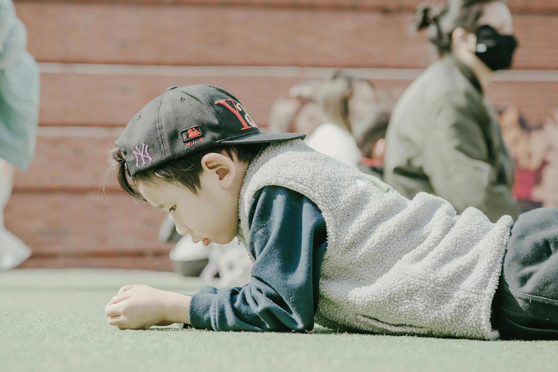 Boy in Sherpa Vest Lying on the Green Carpet