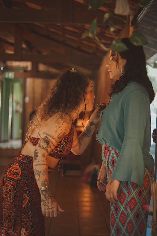 A woman with tattoos on her arm is talking to another woman