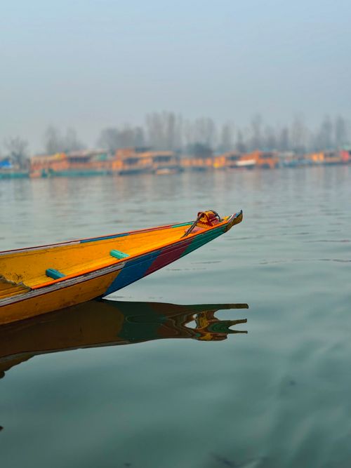 Free A vibrant yellow boat rests peacefully on a calm lake, reflecting serene waters. Stock Photo