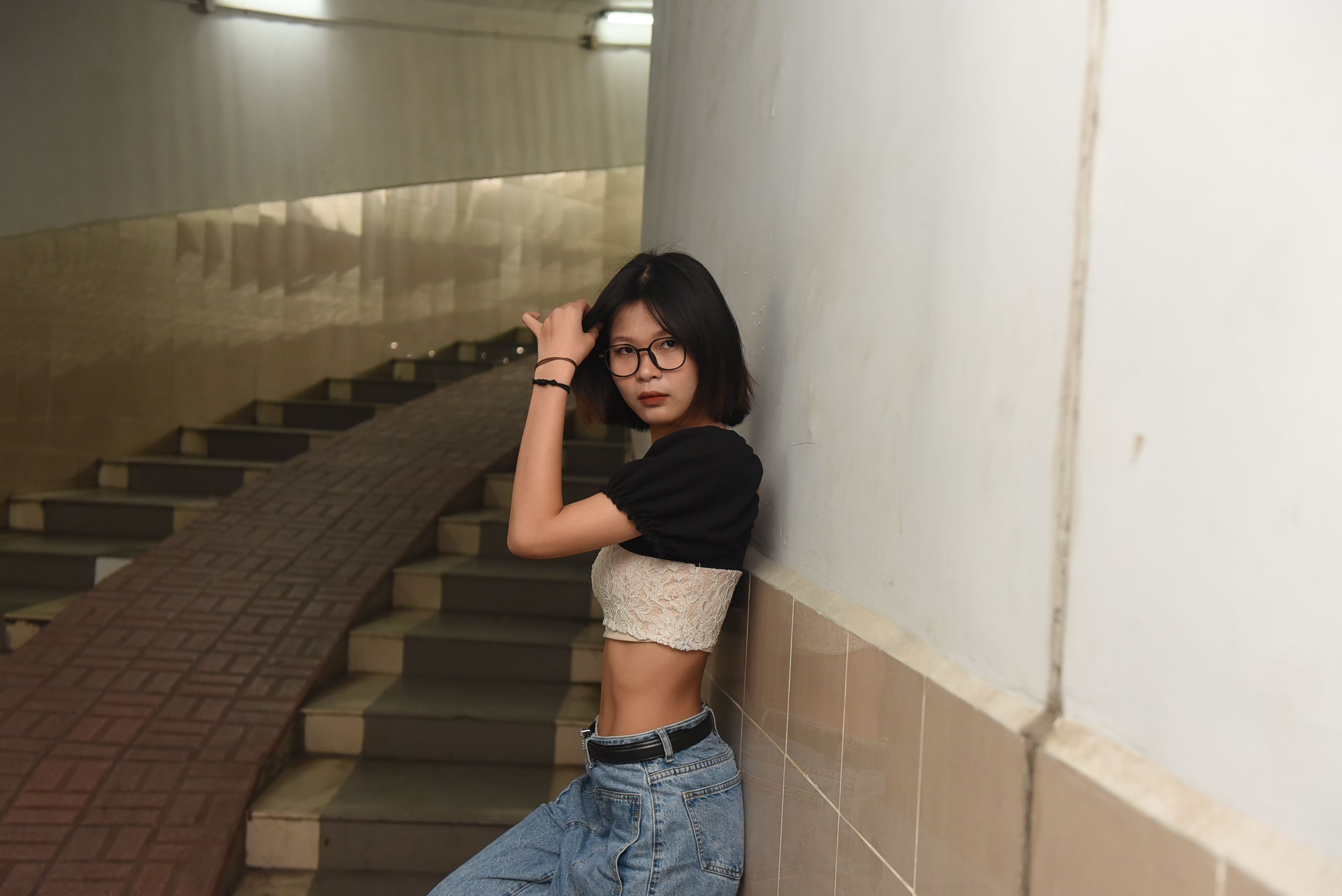 A woman leaning against a wall wearing jeans and a crop top · Free ...