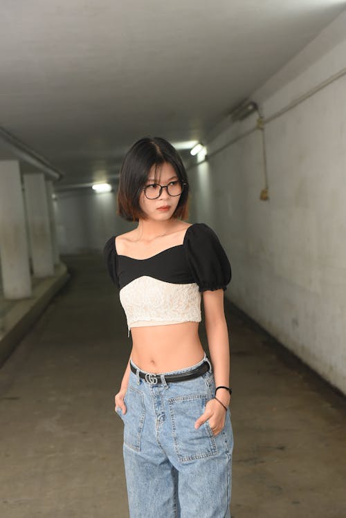 A woman in a crop top and jeans standing in an underground parking garage
