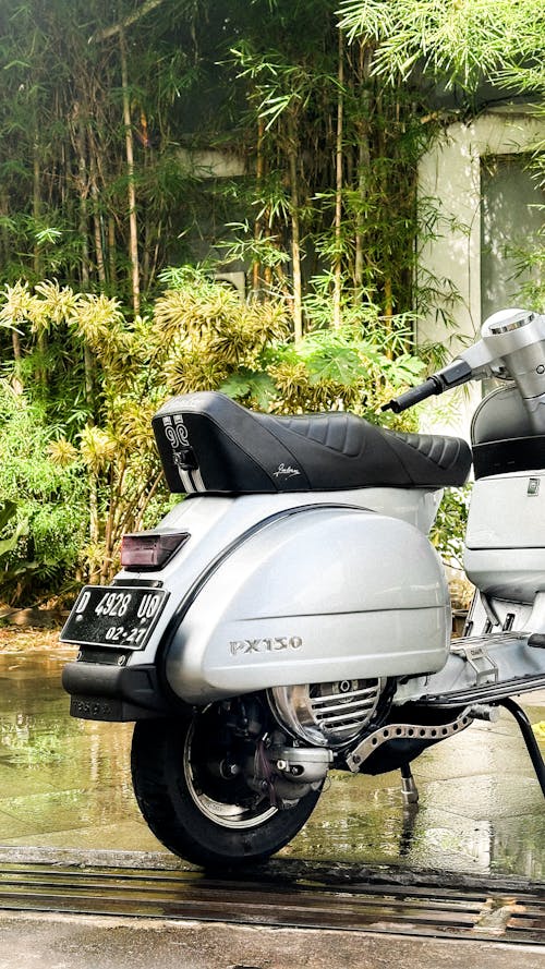 A silver and black vespa parked on a wet road