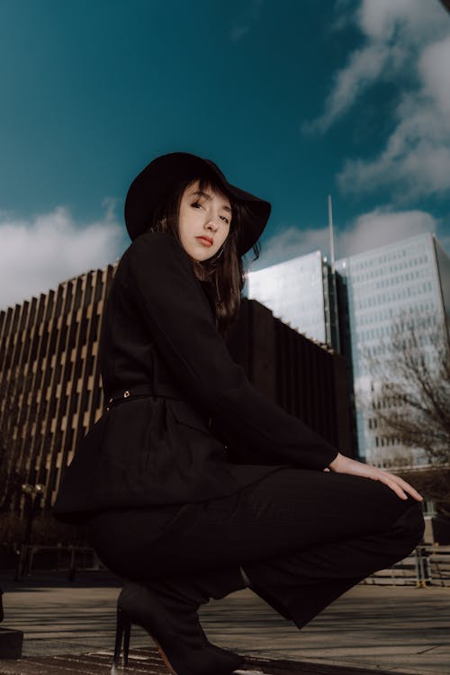 A woman in a black hat and black pants crouches down