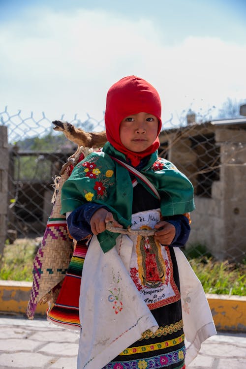 A young girl in a colorful outfit holding a bag