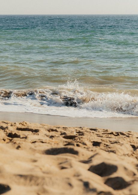 Peaceful sandy beach with gentle ocean waves under a clear sky.