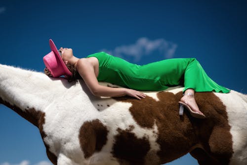 A woman in a green dress laying on top of a horse