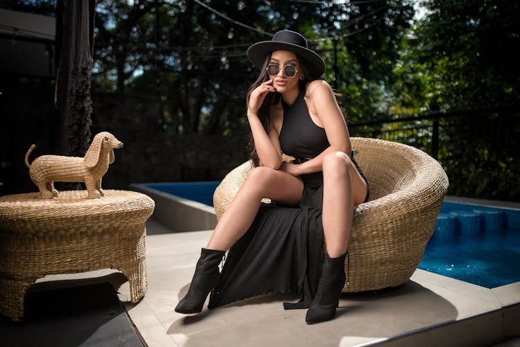 Woman In Black Dress Sitting By Swimming Pool