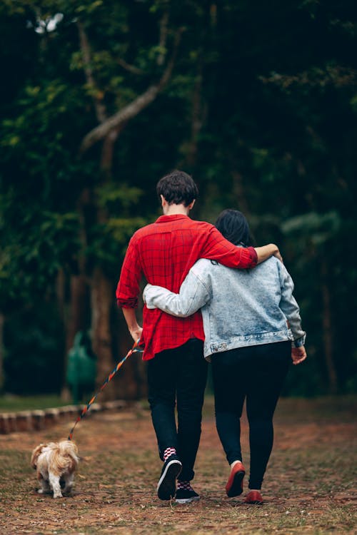 Free Man and Woman Holding Each Other Walking With Dog Stock Photo