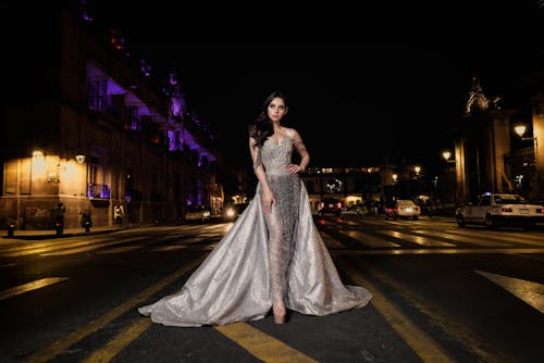 A woman in a silver gown standing on the street