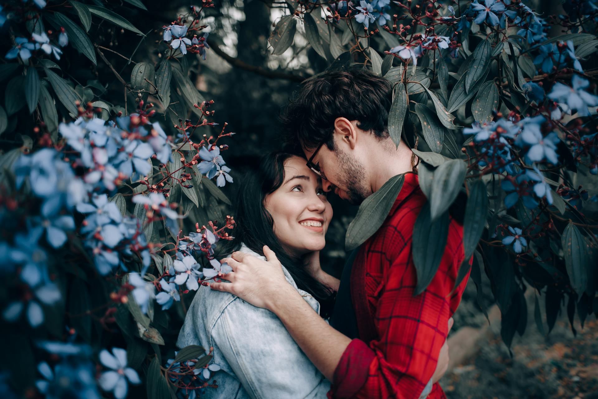 A couple shares a tender moment surrounded by vibrant flowers in a springtime garden.