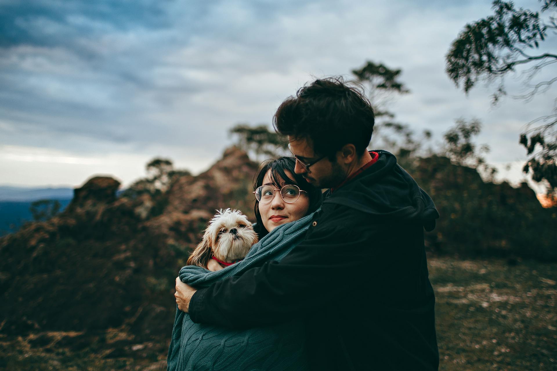 Un couple embrasse un tan adulte et un shih tzu blanc