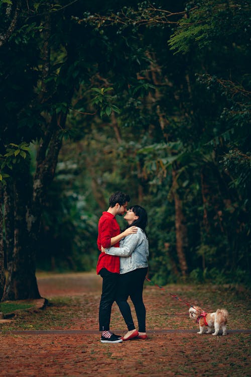 Мужчина и женщина целуются, держа собаку на поводке