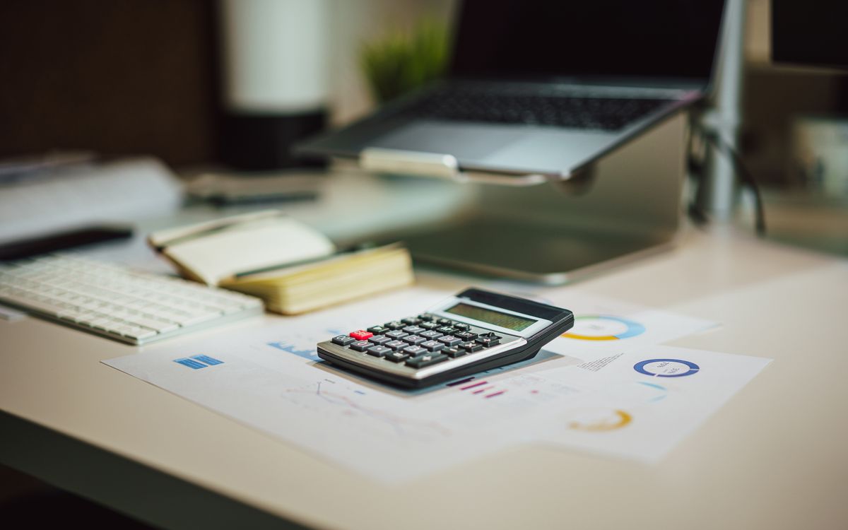 Modern workspace with a calculator, laptop and financial documents arranged on a desk