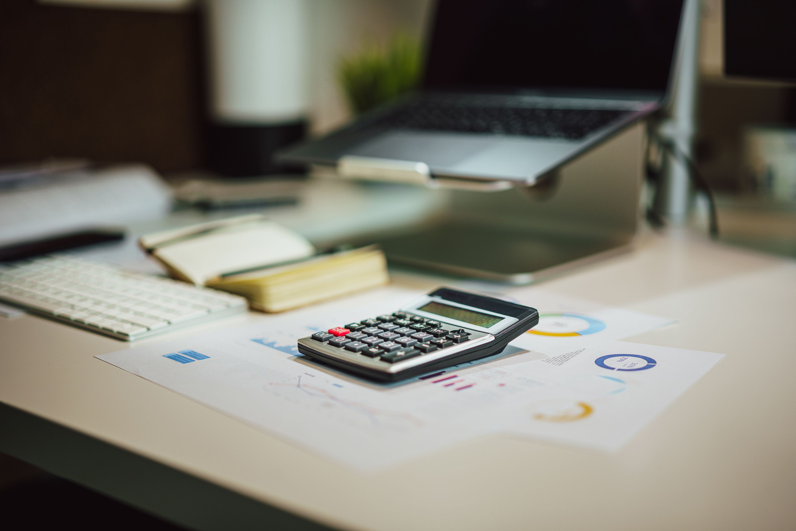 A modern workspace with a laptop, calculator, and documents on a desk, perfect for finance tasks