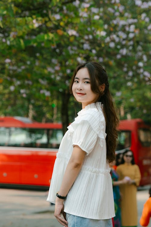 A young asian woman standing in front of a bus