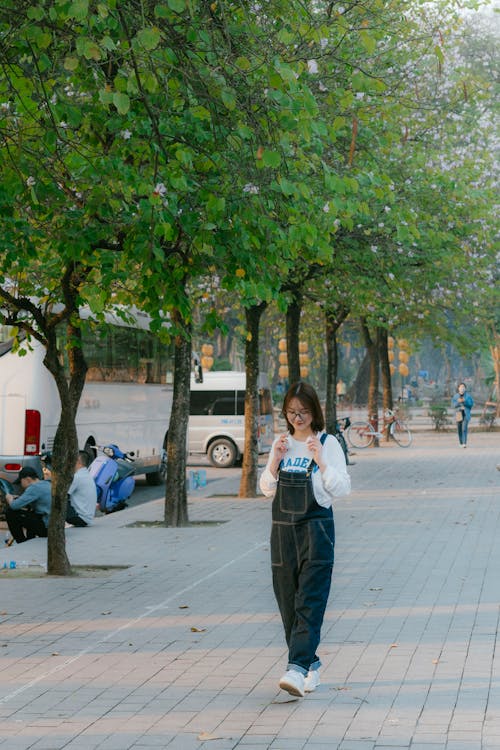 A woman walking down a sidewalk with a cell phone