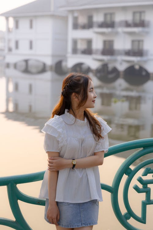 A woman standing on a bridge near a pond