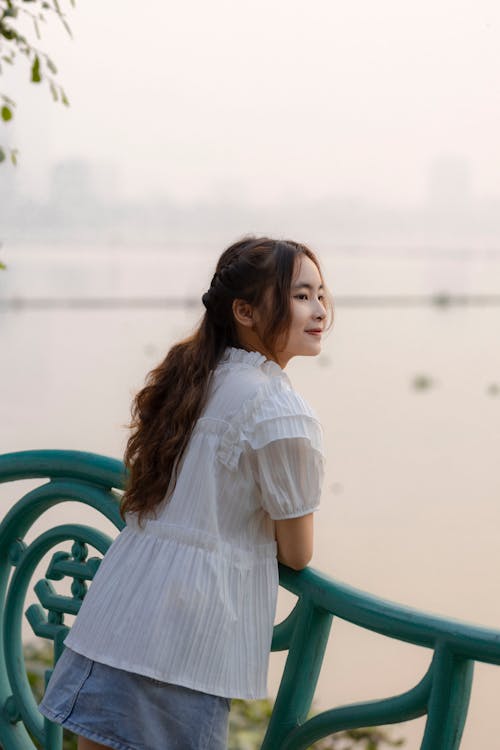 A woman is standing on the railing of a bridge