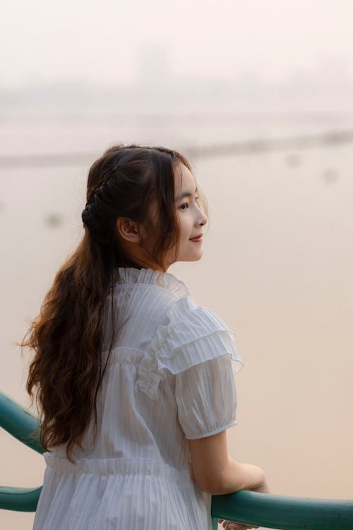 Free A woman in a white dress looking out over the water Stock Photo