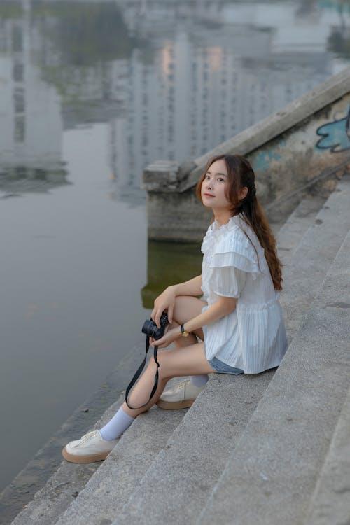 A woman sitting on the steps of a river